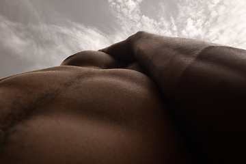 Image showing Detailed texture of human skin. Close up shot of young african-american male body like landscape with the sky background