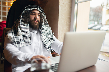 Image showing Arabian businessman working in office, business centre using devicesm gadgets. Lifestyle