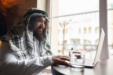 Image showing Arabian businessman working in office, business centre using devicesm gadgets. Lifestyle