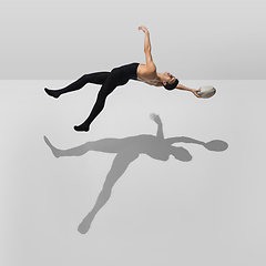 Image showing Beautiful young male athlete practicing on white studio background with shadows in jump, air flying