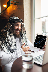 Image showing Arabian businessman working in office, business centre using devicesm gadgets. Lifestyle