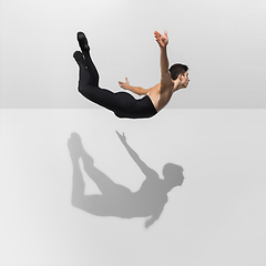 Image showing Beautiful young male athlete practicing on white studio background with shadows in jump, air flying