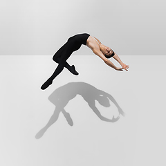 Image showing Beautiful young male athlete practicing on white studio background with shadows in jump, air flying