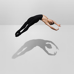 Image showing Beautiful young male athlete practicing on white studio background with shadows in jump, air flying