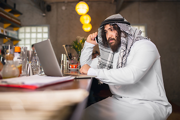 Image showing Arabian businessman working in office, business centre using devicesm gadgets. Lifestyle