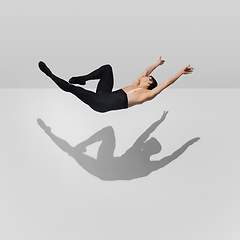 Image showing Beautiful young male athlete practicing on white studio background with shadows in jump, air flying