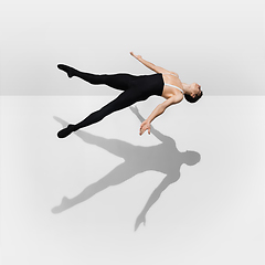 Image showing Beautiful young male athlete practicing on white studio background with shadows in jump, air flying