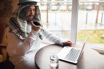 Image showing Arabian businessman working in office, business centre using devicesm gadgets. Lifestyle