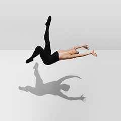 Image showing Beautiful young male athlete practicing on white studio background with shadows in jump, air flying