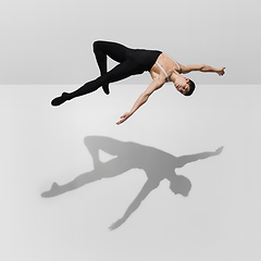 Image showing Beautiful young male athlete practicing on white studio background with shadows in jump, air flying