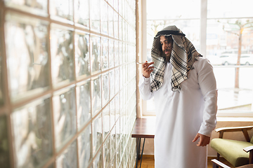 Image showing Arabian businessman working in office, business centre using devicesm gadgets. Lifestyle