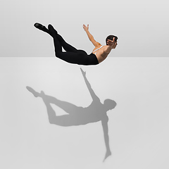 Image showing Beautiful young male athlete practicing on white studio background with shadows in jump, air flying