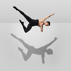 Image showing Beautiful young male athlete practicing on white studio background with shadows in jump, air flying