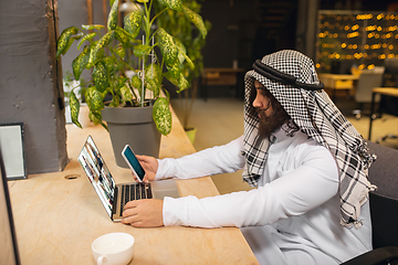 Image showing Arabian businessman working in office, business centre using devicesm gadgets. Lifestyle