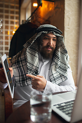 Image showing Arabian businessman working in office, business centre using devicesm gadgets. Lifestyle