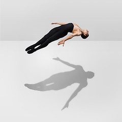 Image showing Beautiful young male athlete practicing on white studio background with shadows in jump, air flying