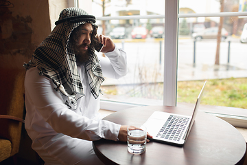 Image showing Arabian businessman working in office, business centre using devicesm gadgets. Lifestyle