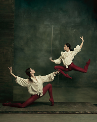 Image showing Two young female ballet dancers like duelists with swords. Ballet and contemporary choreography concept. Creative art photo.