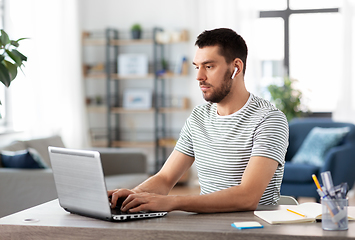 Image showing man with laptop and earphones at home office