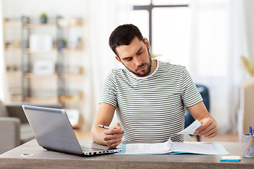 Image showing man with papers and laptop working at home office