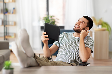 Image showing happy man with tablet pc and earphones at home