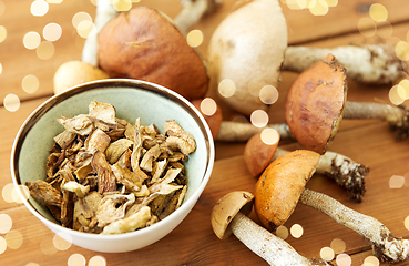 Image showing dried mushrooms in bowl on wooden background