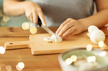 Image showing woman cutting champignons by knife on board