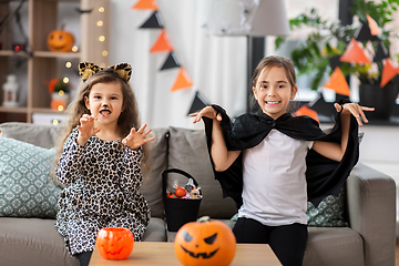 Image showing girls in halloween costumes with candies at home