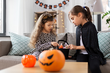 Image showing girls in halloween costumes with candies at home
