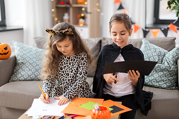 Image showing girls in halloween costumes doing crafts at home