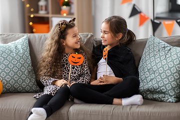 Image showing girls in halloween costumes with pumpkins at home