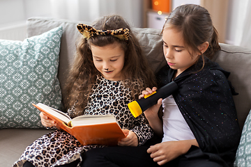 Image showing girls in halloween costumes reading book at home