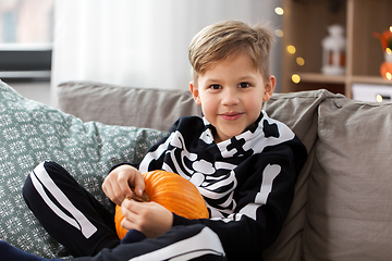 Image showing boy in halloween costume with pumpkin at home