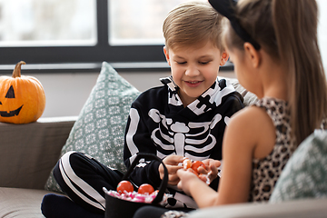 Image showing kids in halloween costumes with candies at home