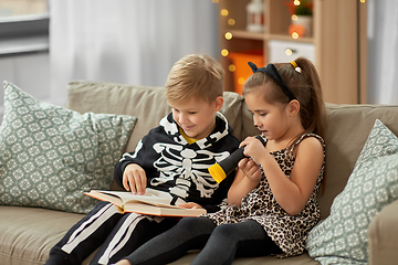 Image showing kids in halloween costumes reading book at home