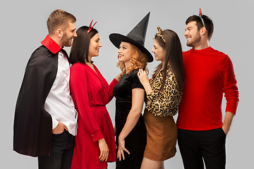 Image showing happy friends in halloween costumes over grey