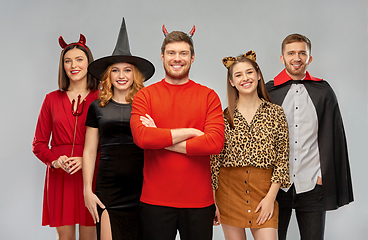 Image showing happy friends in halloween costumes over grey