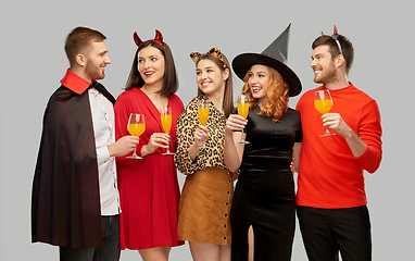 Image showing happy friends in halloween costumes over grey