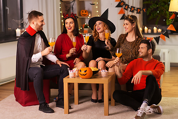 Image showing happy friends in halloween costumes at home party