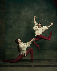 Image showing Two young female ballet dancers like duelists with swords. Ballet and contemporary choreography concept. Creative art photo.