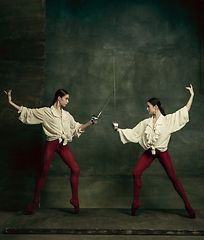 Image showing Two young female ballet dancers like duelists with swords. Ballet and contemporary choreography concept. Creative art photo.