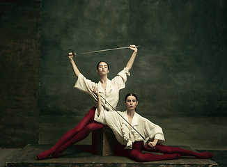 Image showing Two young female ballet dancers like duelists with swords. Ballet and contemporary choreography concept. Creative art photo.