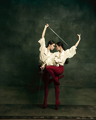 Image showing Two young female ballet dancers like duelists with swords. Ballet and contemporary choreography concept. Creative art photo.