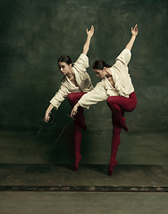 Image showing Two young female ballet dancers like duelists with swords. Ballet and contemporary choreography concept. Creative art photo.