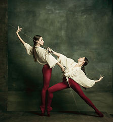 Image showing Two young female ballet dancers like duelists with swords. Ballet and contemporary choreography concept. Creative art photo.