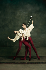 Image showing Two young female ballet dancers like duelists with swords. Ballet and contemporary choreography concept. Creative art photo.