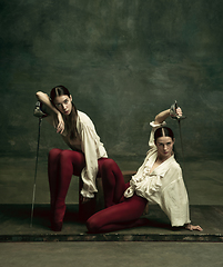 Image showing Two young female ballet dancers like duelists with swords. Ballet and contemporary choreography concept. Creative art photo.