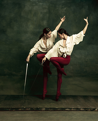 Image showing Two young female ballet dancers like duelists with swords. Ballet and contemporary choreography concept. Creative art photo.