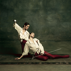 Image showing Two young female ballet dancers like duelists with swords. Ballet and contemporary choreography concept. Creative art photo.