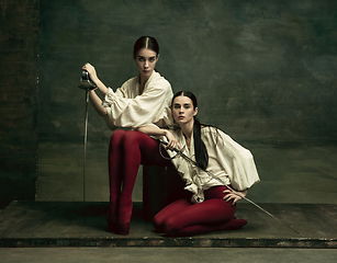 Image showing Two young female ballet dancers like duelists with swords. Ballet and contemporary choreography concept. Creative art photo.